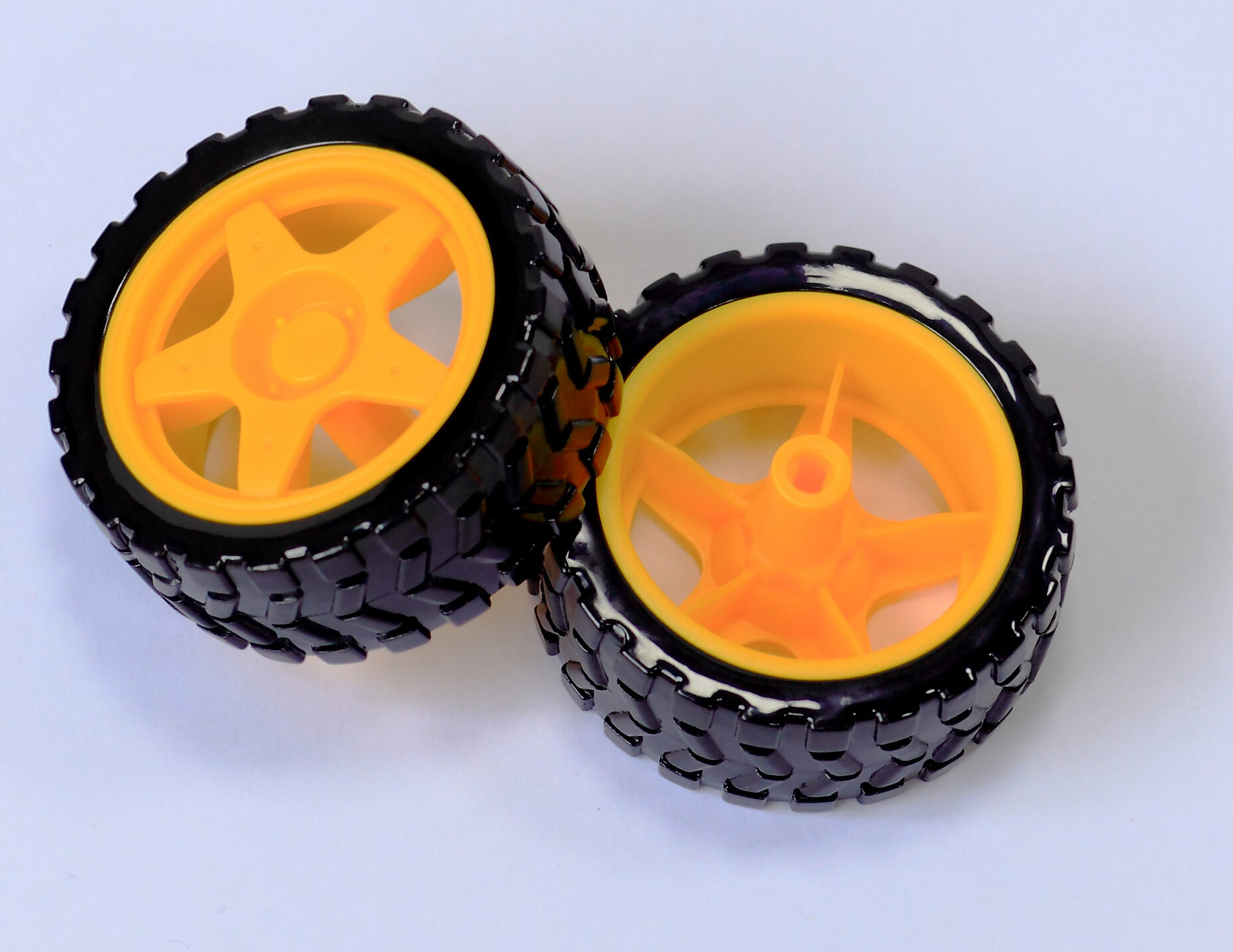 Two black rubber robot wheels with yellow hubs