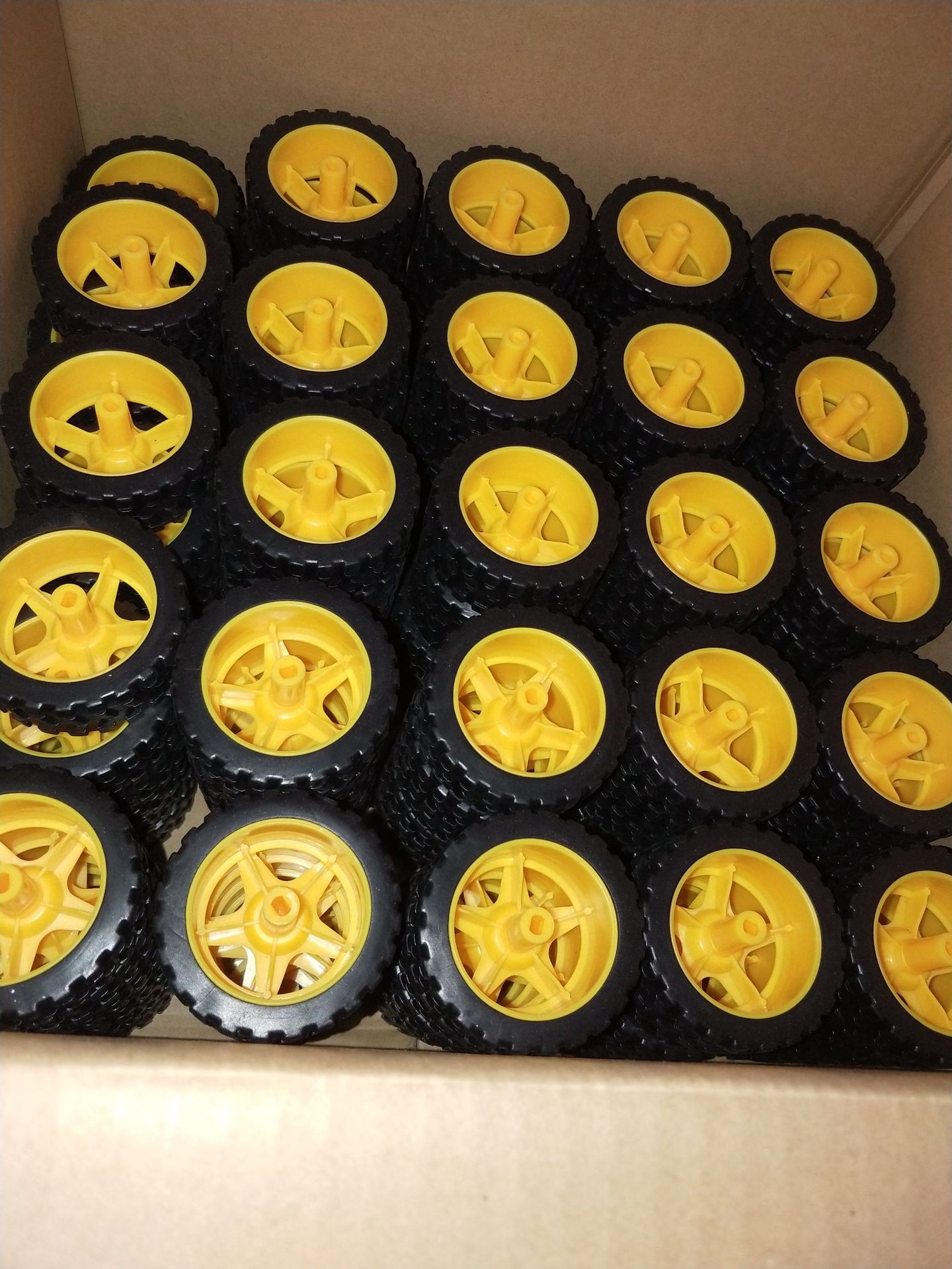 Black rubber robot wheels with yellow hubs packed in a cardboard box