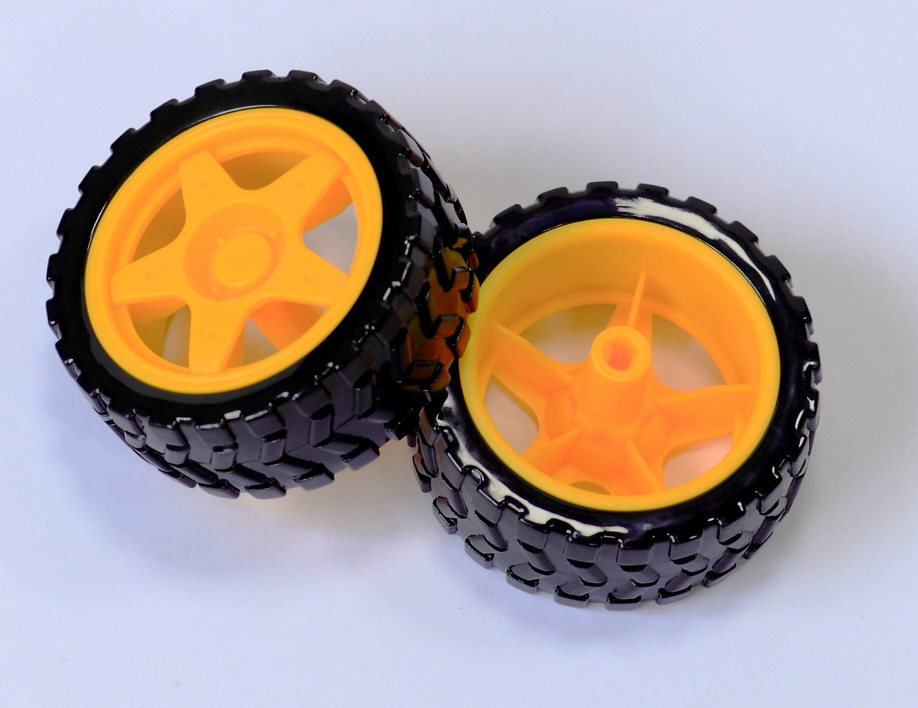 Two black rubber robot wheels with yellow spoked hubs, reverse view