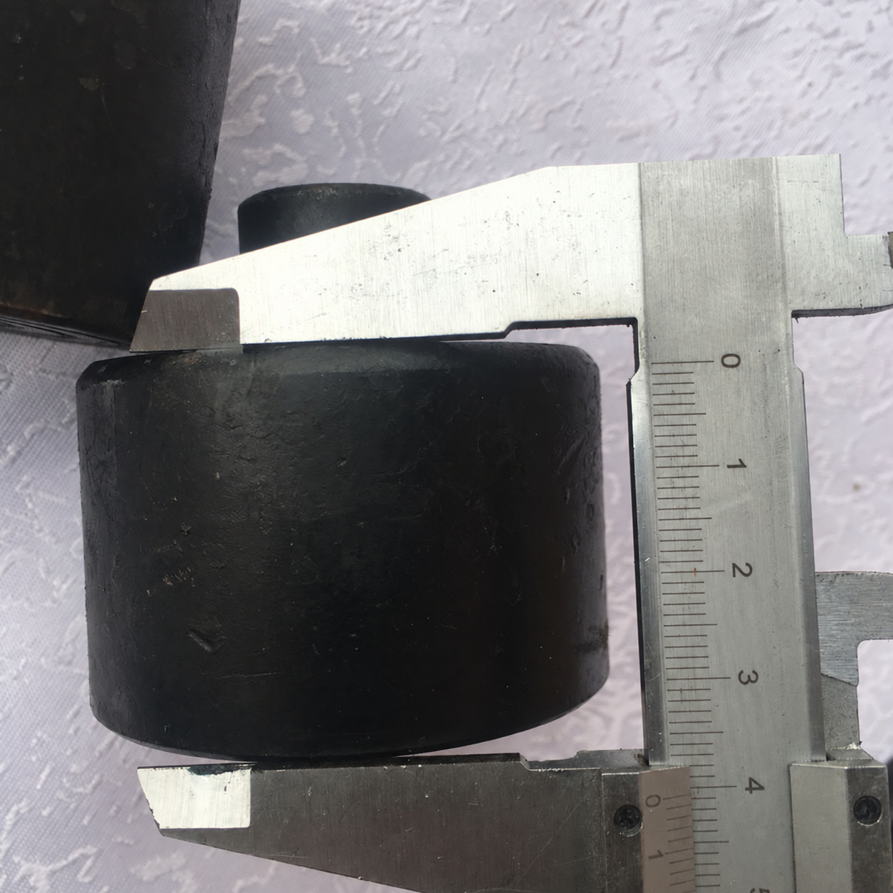 Rubber jack extension pad beside a measuring caliper