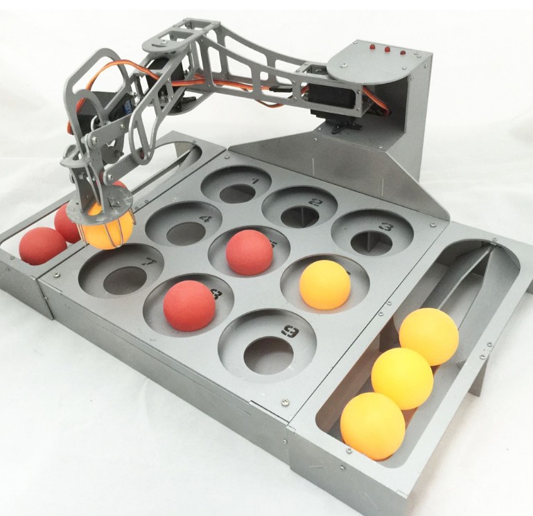 Teaching robot arm with red and yellow balls on a numbered metal tray