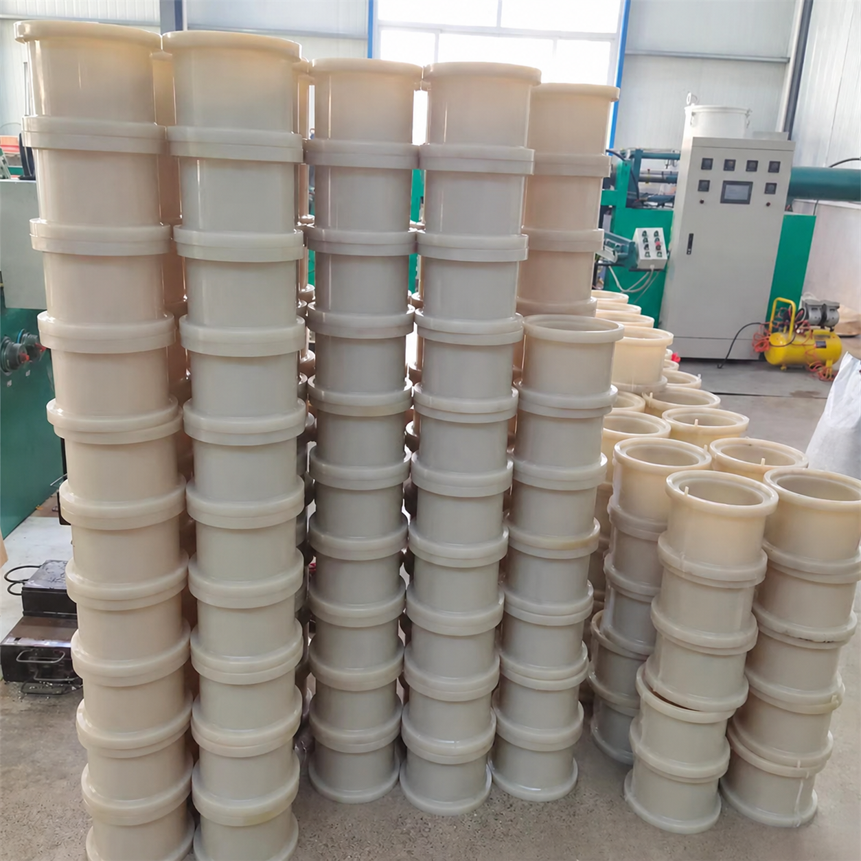 Stacks of white flanged protective sleeves in production